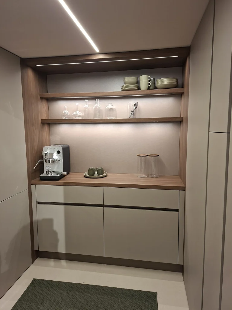 Zona de desayunador integrada en cocina moderna con estanterías iluminadas y mobiliario a medida en Valencia.